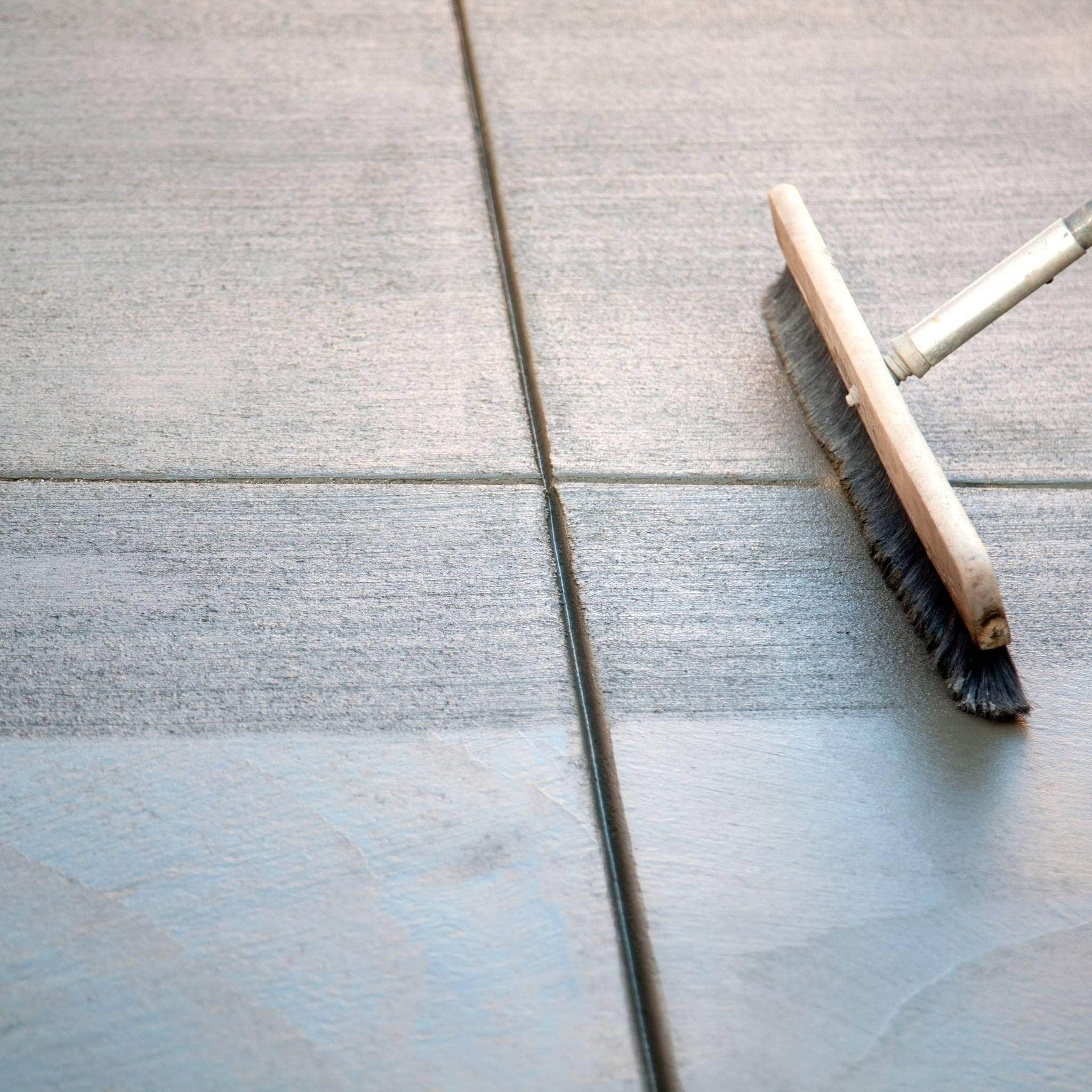 Brush adding texture to freshly poured concrete, showcasing custom concrete work - AllDone Construction.